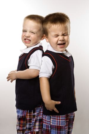 Caucasian twin boys crying standing against white background.の写真素材