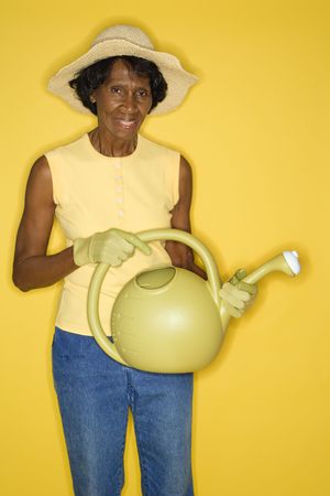 Mature adult African American female holding watering can.の写真素材