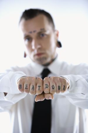 Caucasian mid-adult man with tattoos and piercings holding out fists reading beat down.の写真素材