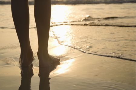 Caucasian person standing barefoot on beach in water.の写真素材