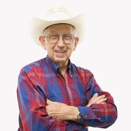 Portrait of smiling Caucasion elderly man wearing plaid shirt and cowboy hat with arms crossed.の写真素材