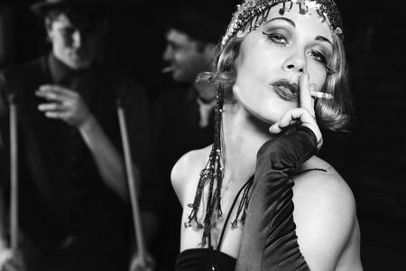 Caucasian prime adult female smoking and standing in front of two Caucasian prime adult men holding pool sticks.の写真素材