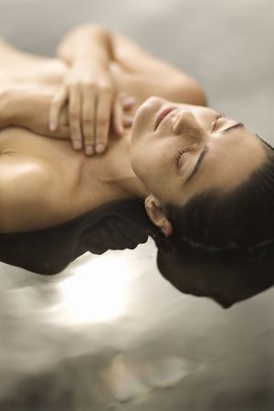 Close up of young  Caucasian woman lying on back in water with eyes closed and hands crossed on chest.の写真素材