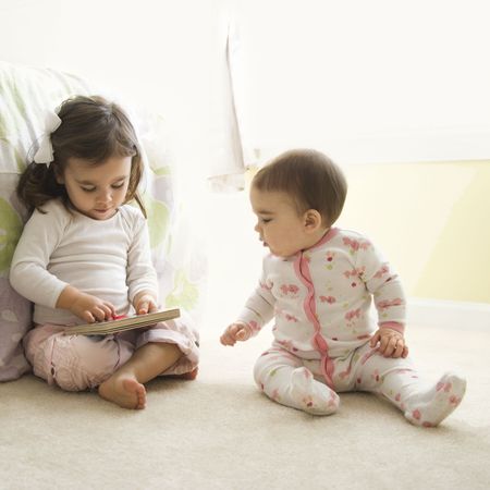 Caucasian girl children sitting on bedroom floor looking at book.の写真素材