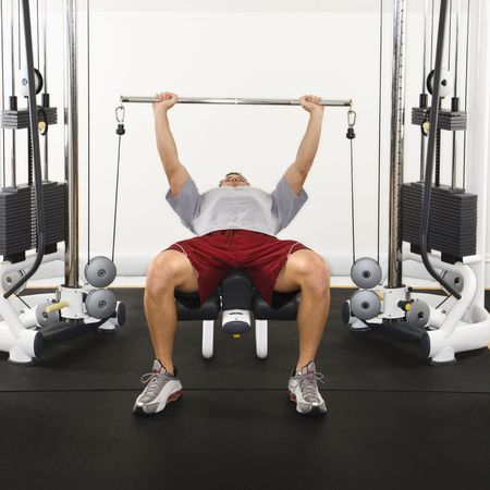 Man at gym lifting weights on weight machine.