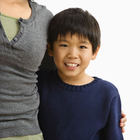 Boy standing smiling with mother standing next to him with arm around him.の写真素材