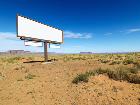 Blank billboard in middle of desert landscape with distant mountains.の写真素材