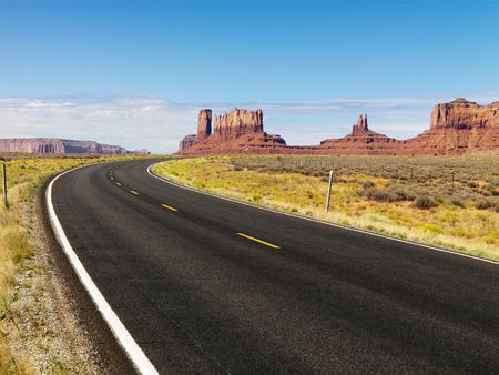 Curve in road in scenic desert road with mesa land formations and mountains.の写真素材