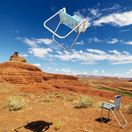 Lawn chair thrown in midair in scenic desert landscape with land formation.の写真素材