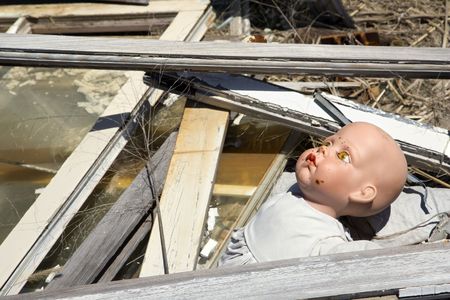 Old  doll head sticking out of garbage at landfill.の写真素材