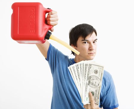 Asian young man holding gas can pouring gasoline onto money.の写真素材