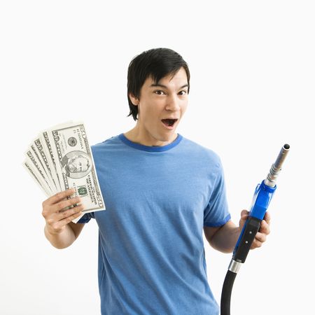 Asian young man with happy expression holding money and gas pump nozzle.の写真素材