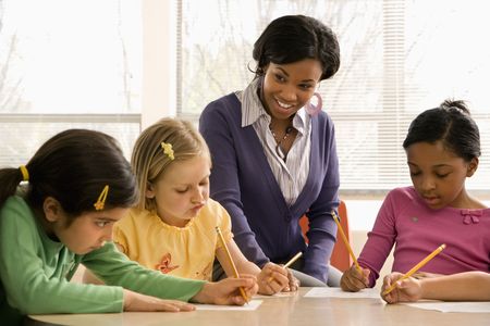 Teacher helping students in school classroom. Horizontally framed shot.