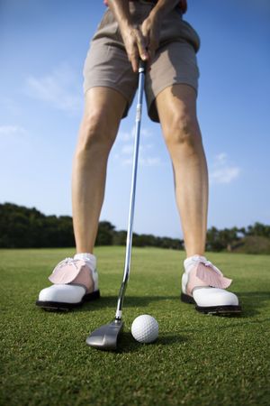 Closeup of a woman golfer about to putt on a golf green. Vertical shot.