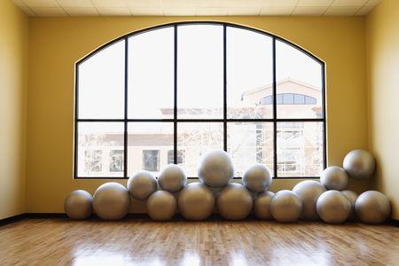 Balance balls stacked on the floor in front of a large window at the gym. Horizontal shot.の写真素材