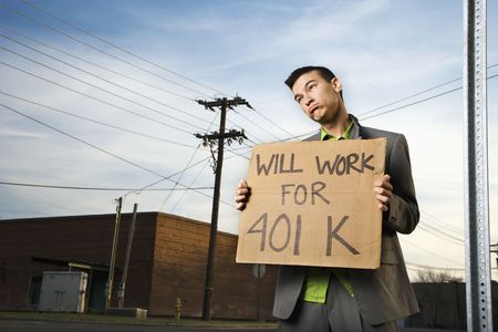 Young businessman stands on a street corner holding a sign that reads 'will work for 401 K'. Horizontal shot.の写真素材