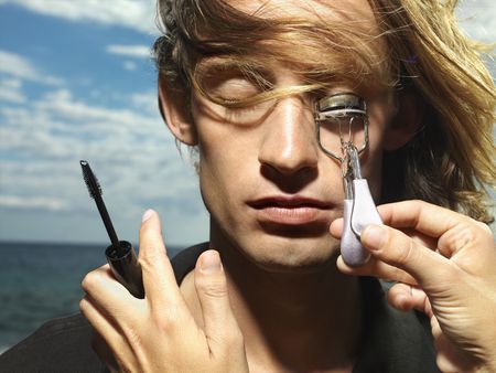 Young man with wind blown hair having his eyelashes curled with the ocean in the background. Horizontal shot.の写真素材