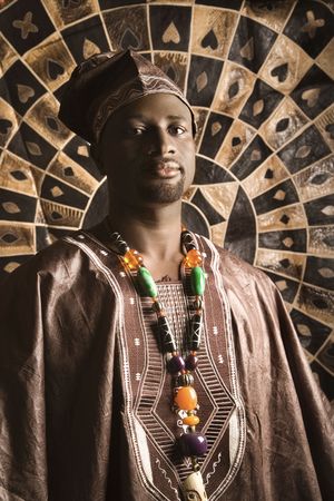 Portrait of an African American man wearing traditional African clothing, in front of a patterned wall and looking at the camera. Vertical format.の写真素材