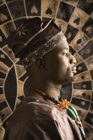 Profile portrait of an African American man wearing traditional African clothing, in front of a patterned wall. Vertical format.の写真素材