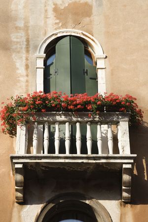 Low angle view of arched window with balcony and flowers in Venice, Italy. Vertical shot.の写真素材