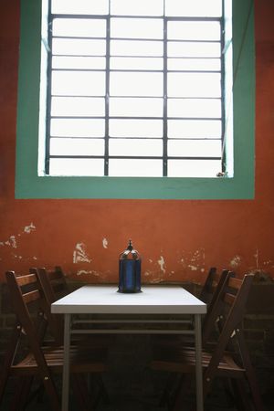 A simple table sitting under a window against a rustic wall. Vertical shot.の写真素材