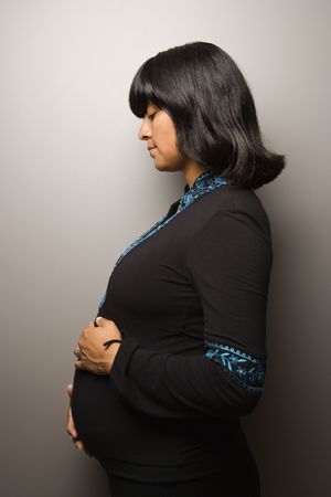 Profile portrait pregnant woman with her hands on her belly. Vertical shot. Isolated on gray.