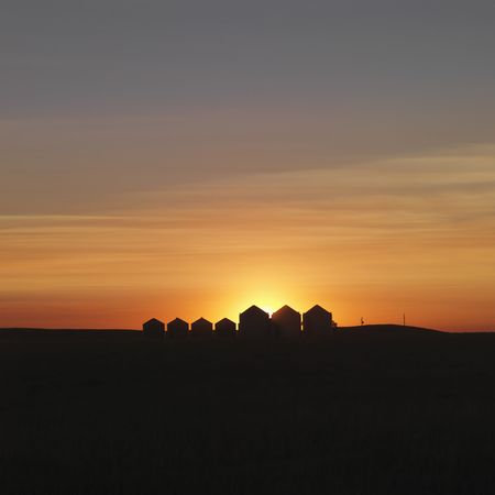 Row of rural houses in the distance, silhouetted against the setting sun. Square shot.の写真素材
