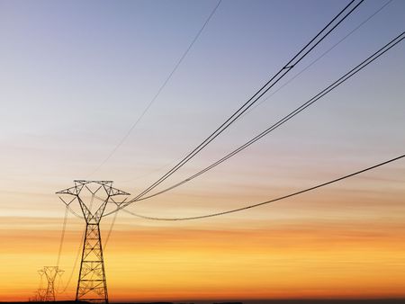 Line of electrical towers and power lines at sunset. Horizontal shot.の写真素材