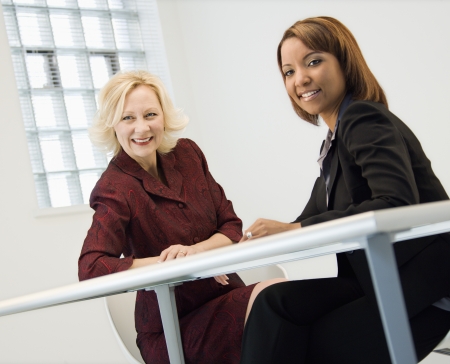 Portrait of businesswomen sitting at office desk smiling.の写真素材