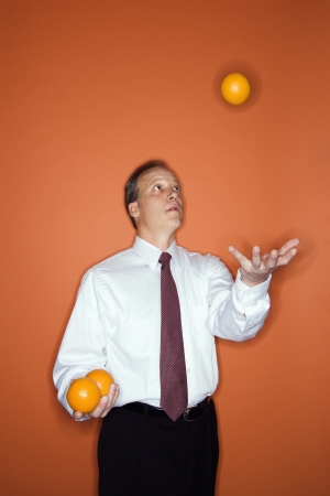 Caucasian middle aged businessman juggling oranges.の写真素材