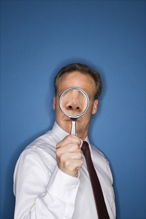 Caucasian middle aged businessman looking through magnifying glass.の写真素材