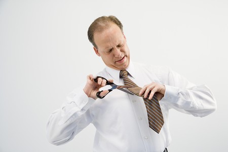 Caucasian middle aged businessman cutting off necktie with scissors.の写真素材