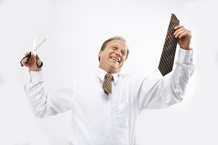 Caucasian middle aged businessman holding cut off necktie and scissors smiling.の写真素材