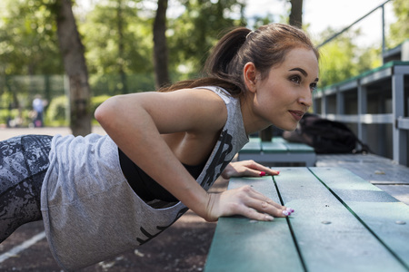 Beautiful brunette girl doing workout on the bench in trainingの写真素材
