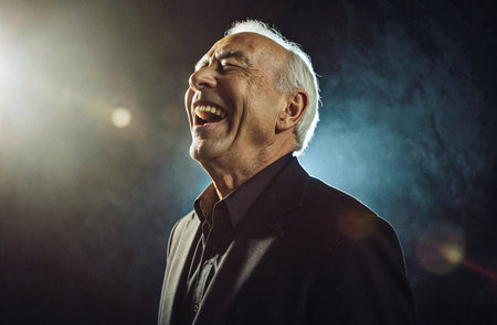 Portrait of a senior man laughing in a dark room with smoke.の素材