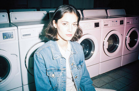 Portrait of a young woman in front of the washing machine.の素材