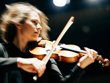Young female violinist playing on the stage. Close-up.の素材
