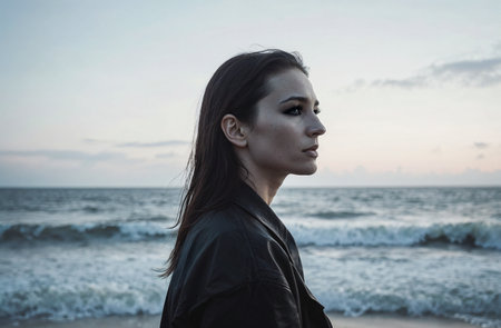 Beautiful girl in a black jacket on the beach at sunset.の素材