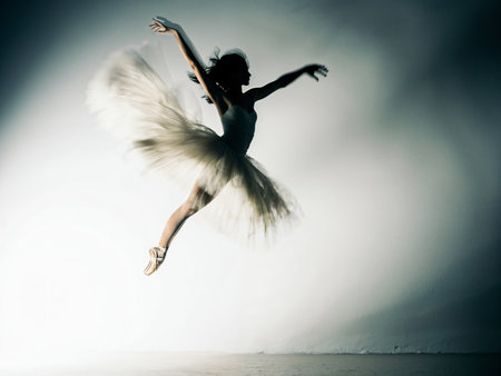Beautiful ballerina in white tutu and pointe shoes dancing on gray studio backgroundの素材