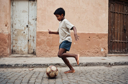 African boy playing soccer on the street of the old town of Goaの素材