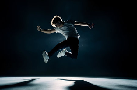 Young man dancing breakdance on black studio background. Breakdance concept.の素材