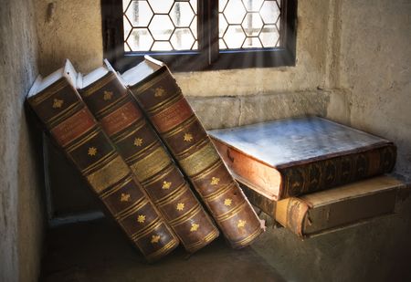 Pile of ancient books in front of windowの写真素材