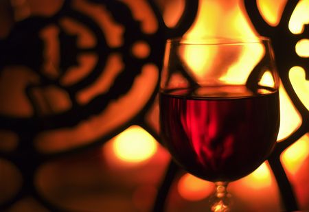 Glass of wine in front of the fireplace. Selective focus, yellow glow from the fire.の写真素材