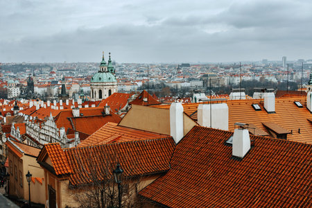 A scenic cityscape of Prague with red rooftops, historic architecture, and a cloudy sky, capturing the charm of the old European townの写真素材