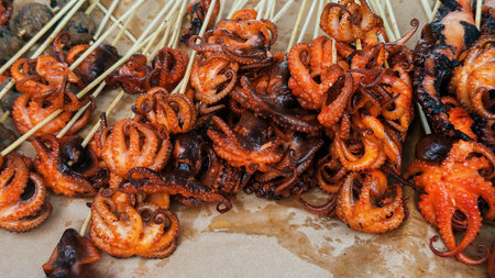 Grilled octopus skewers with curled tentacles displayed as traditional street food on a market tray.