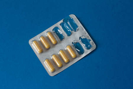 partly empty blister with yellow capsules on blue backgound. High quality photoの写真素材