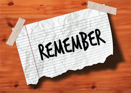 REMEMBER handwritten on torn notebook page crumpled paper on wood texture background. Illustrationの写真素材