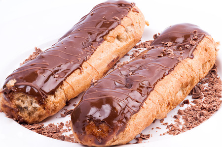 Two eclairs with chocolate lakes isolated on a white plate and white background