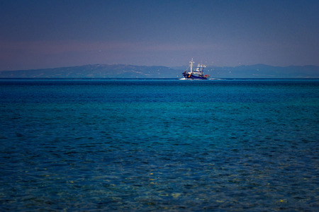 Fishing boat on the blue Aegean Sea in Samothrace Island in Greece with sea gulls surrounding it...