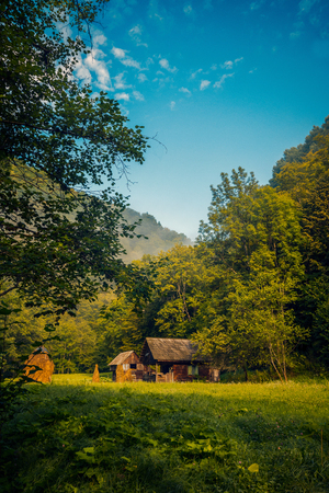 Small house found near a forest and a haystack near the house against a blue sky in the countrysideの写真素材